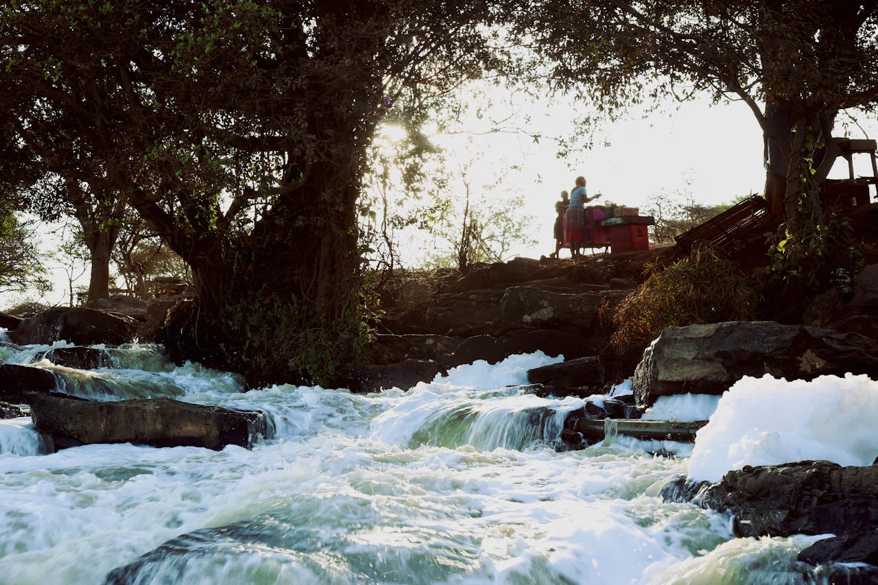 A captivating waterfall surrounded by trees and a vendor stall in a tranquil setting.